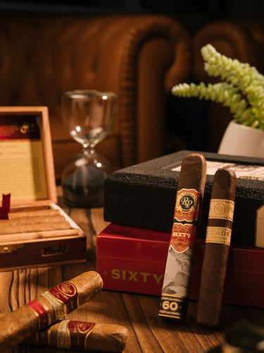 Cigars with a humidor and glass on a wooden table