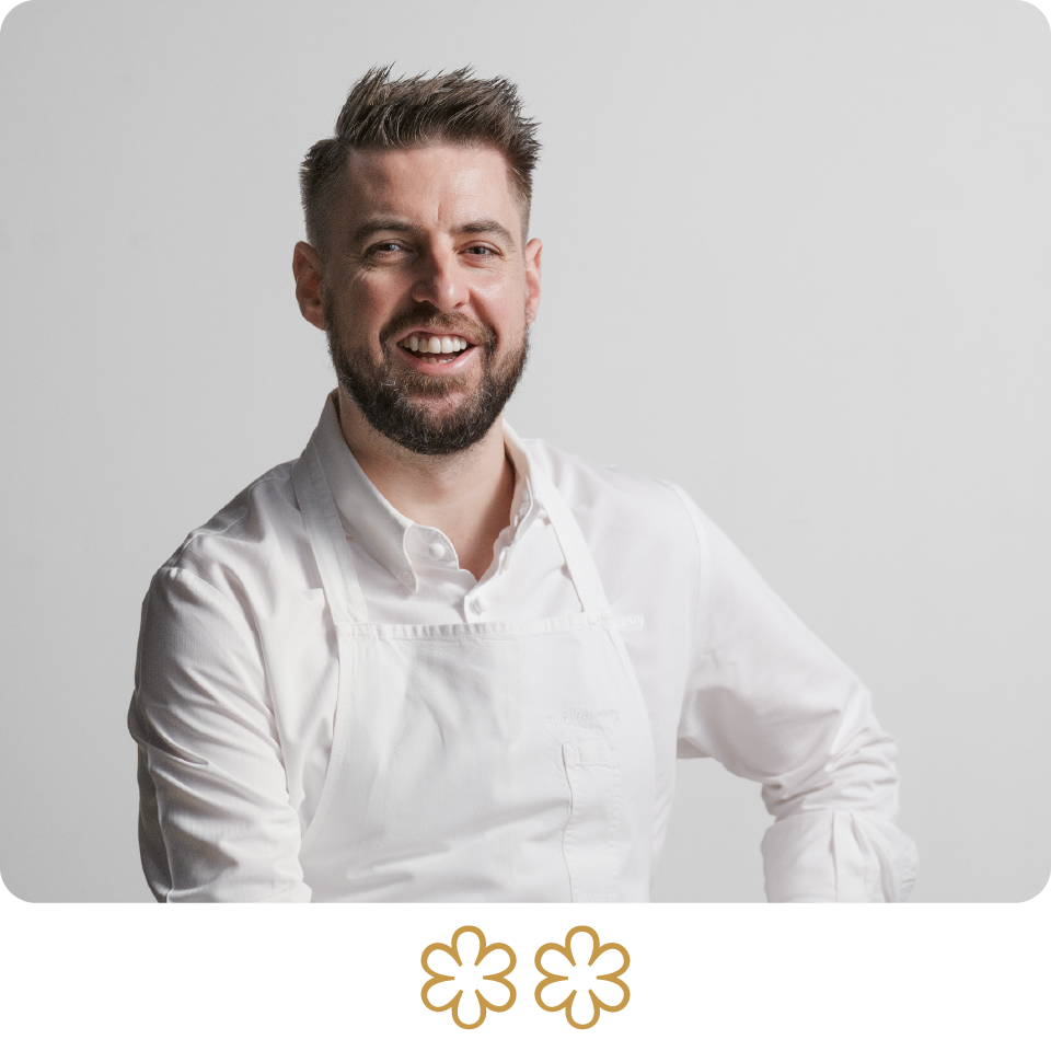 Man wearing a white chef's coat against a light gray background