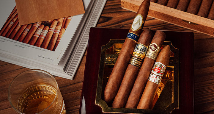 Cigar box with cigars and a glass of whiskey on a wooden table