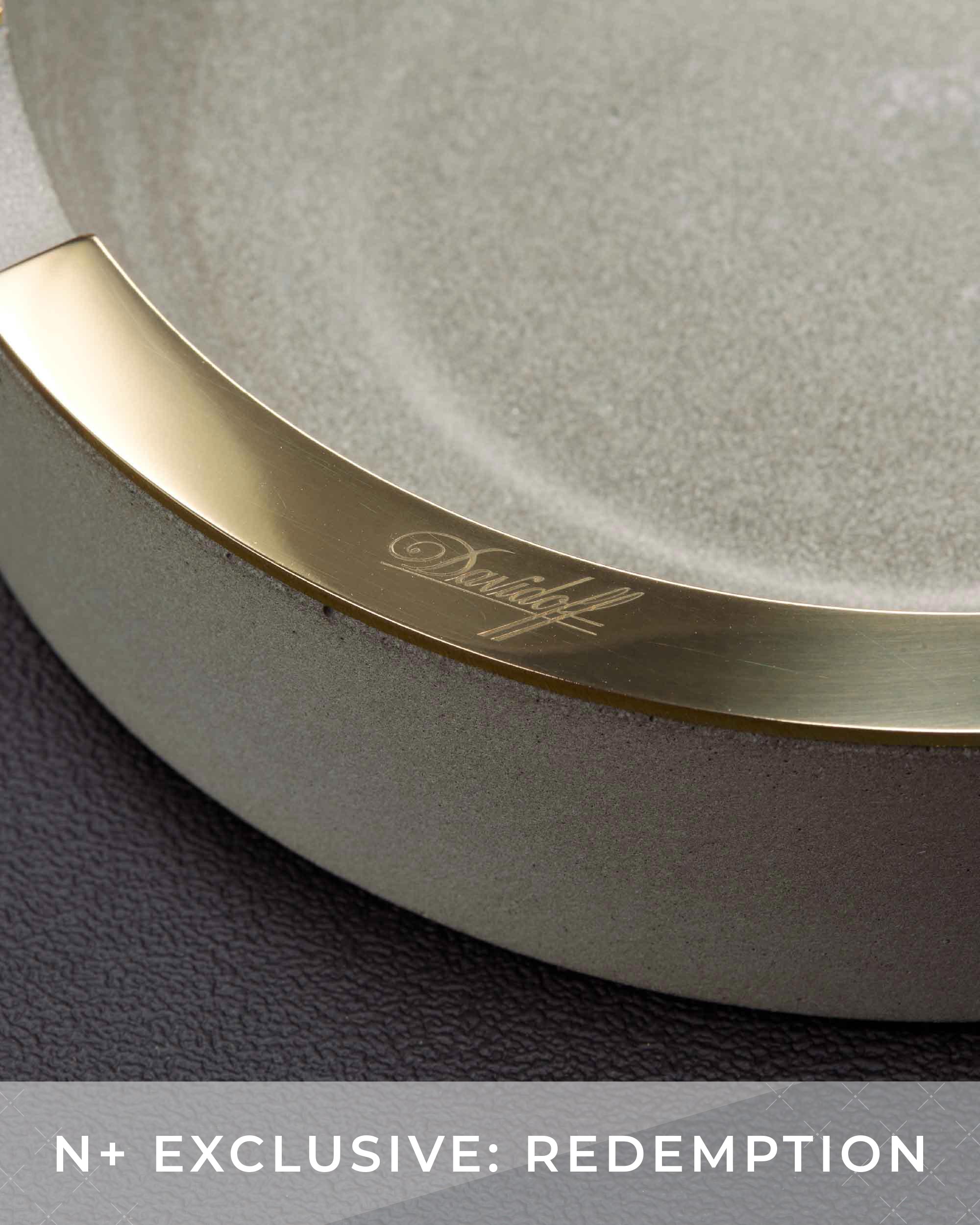 Round mirror with gold frame and 'Dunhill' branding on a dark background