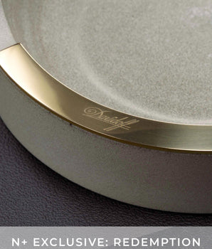 Round mirror with gold frame and 'Dunhill' branding on a dark background
