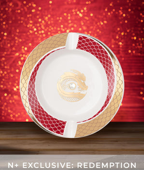 Decorative plate with a central emblem on a wooden surface against a red background