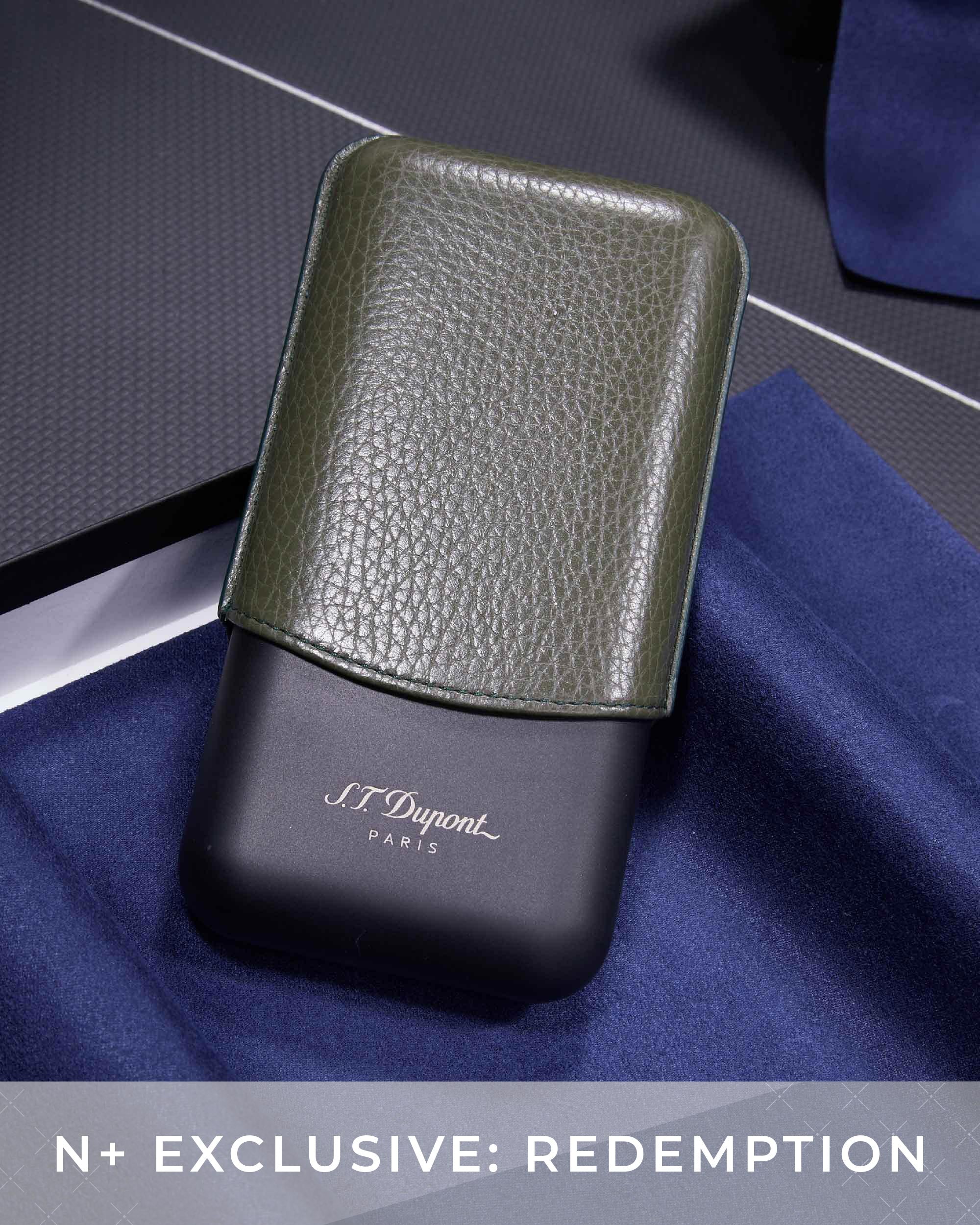Green leather case on a black base with 'J.L. Dupont' branding, placed on a blue fabric background.