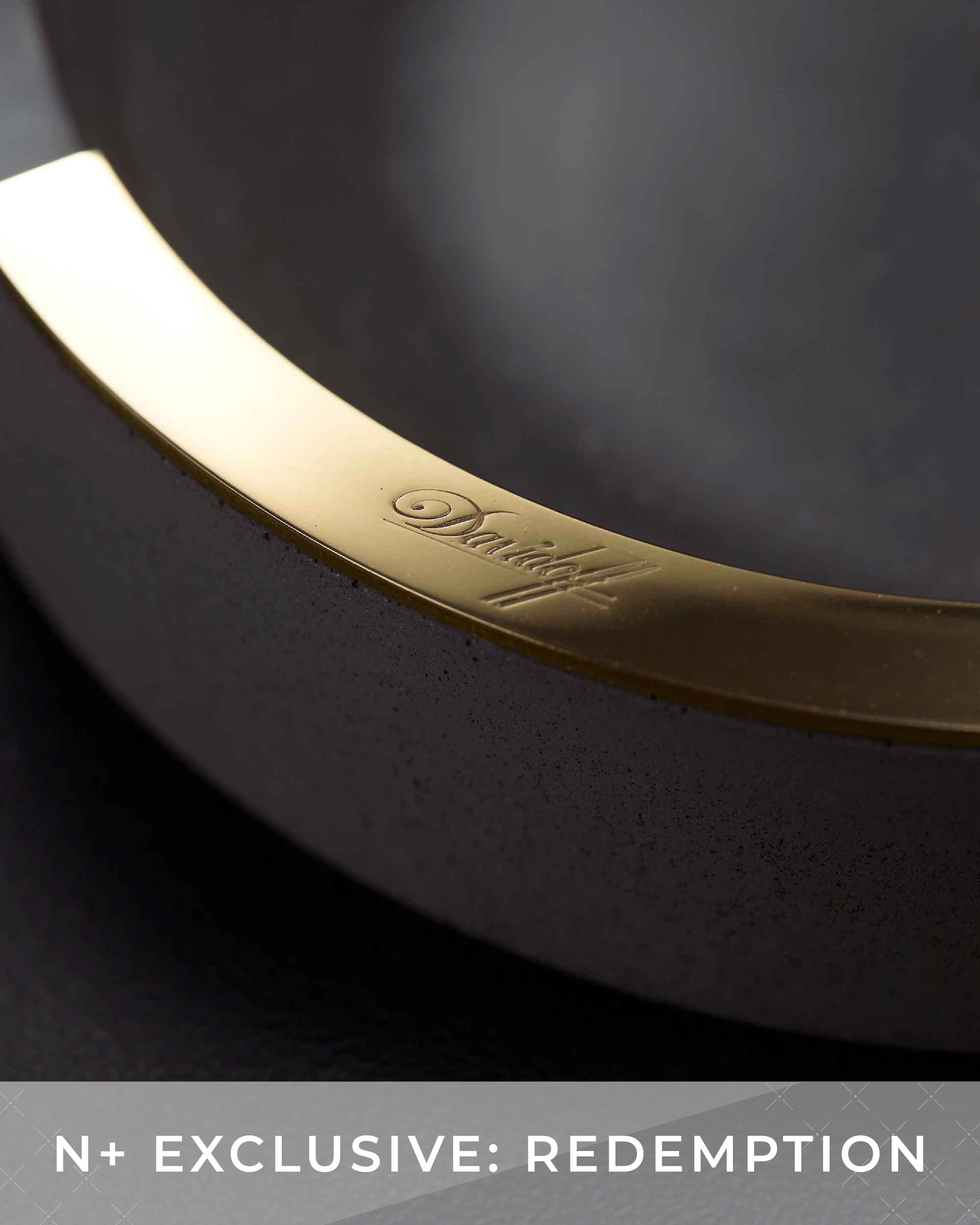 Close-up of a black rim with gold accent and brand logo on a dark background.