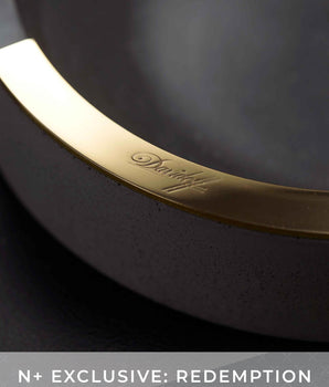 Close-up of a black rim with gold accent and brand logo on a dark background.