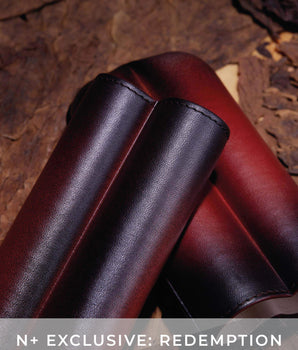 Close-up of brown leather boots on a textured surface with 'N+ Exclusive: Redemption' text.