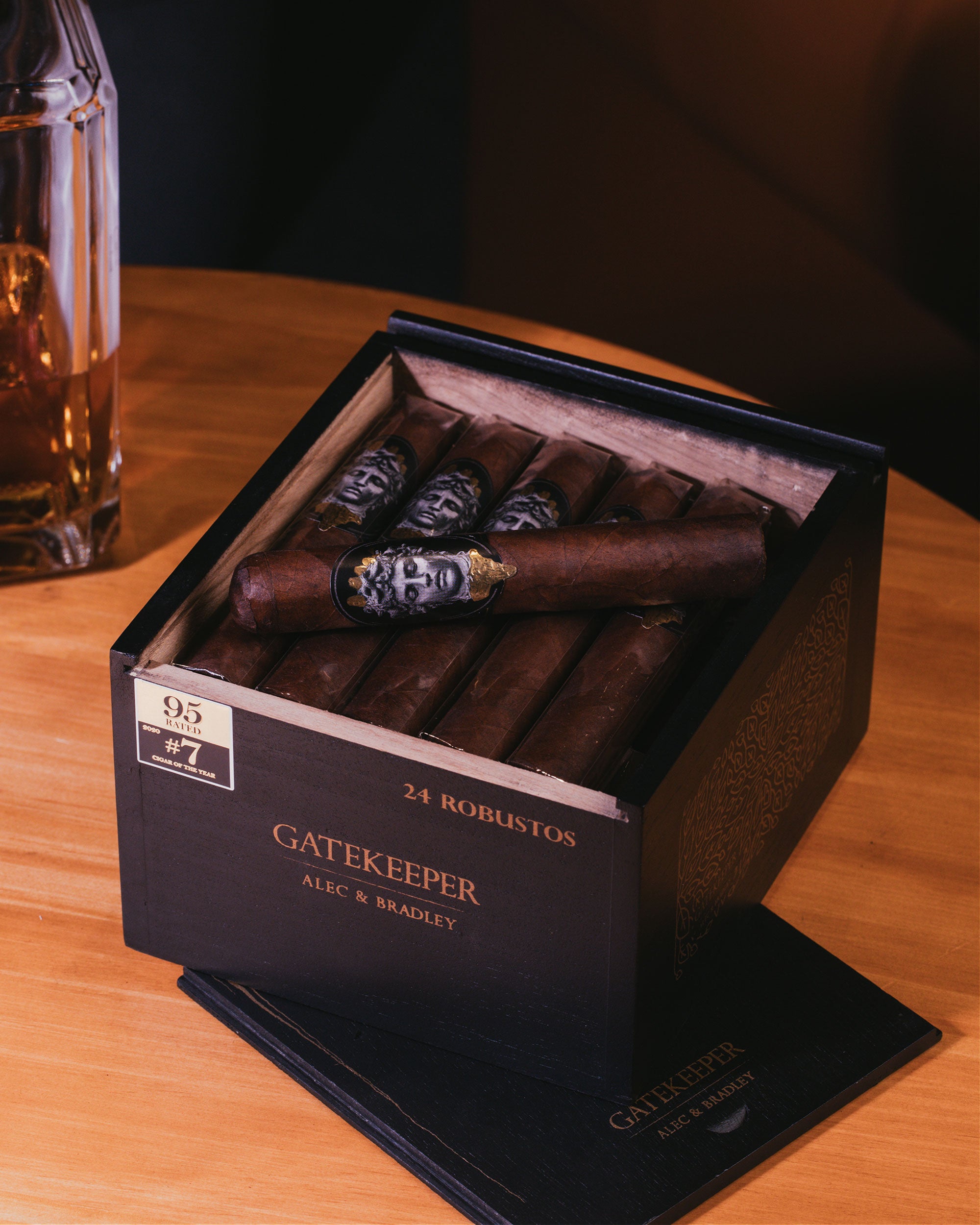 Box of Alec & Bradley Gatekeeper cigars on a wooden table with a glass of beer.