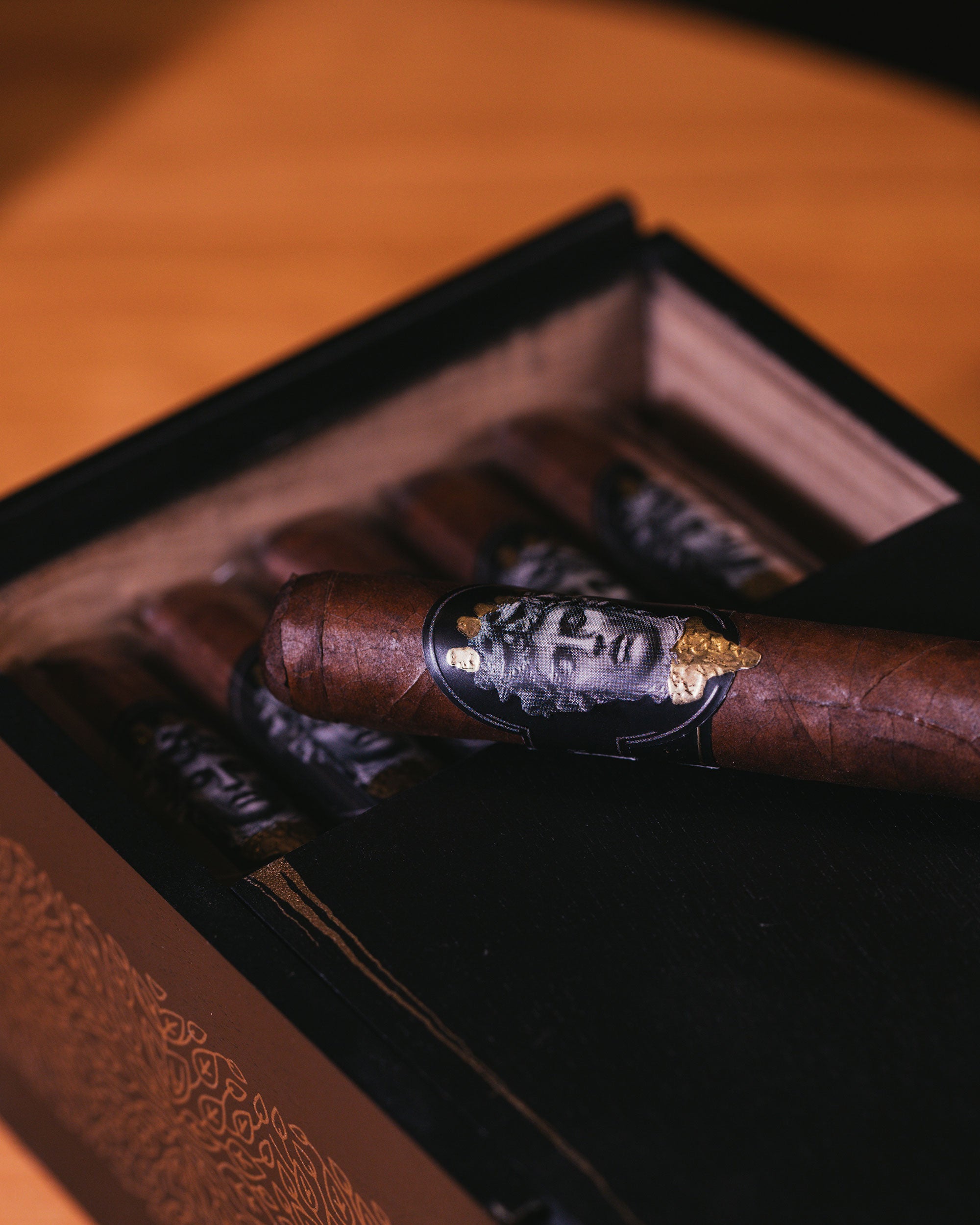 Cigar with a decorative band in an open wooden humidor