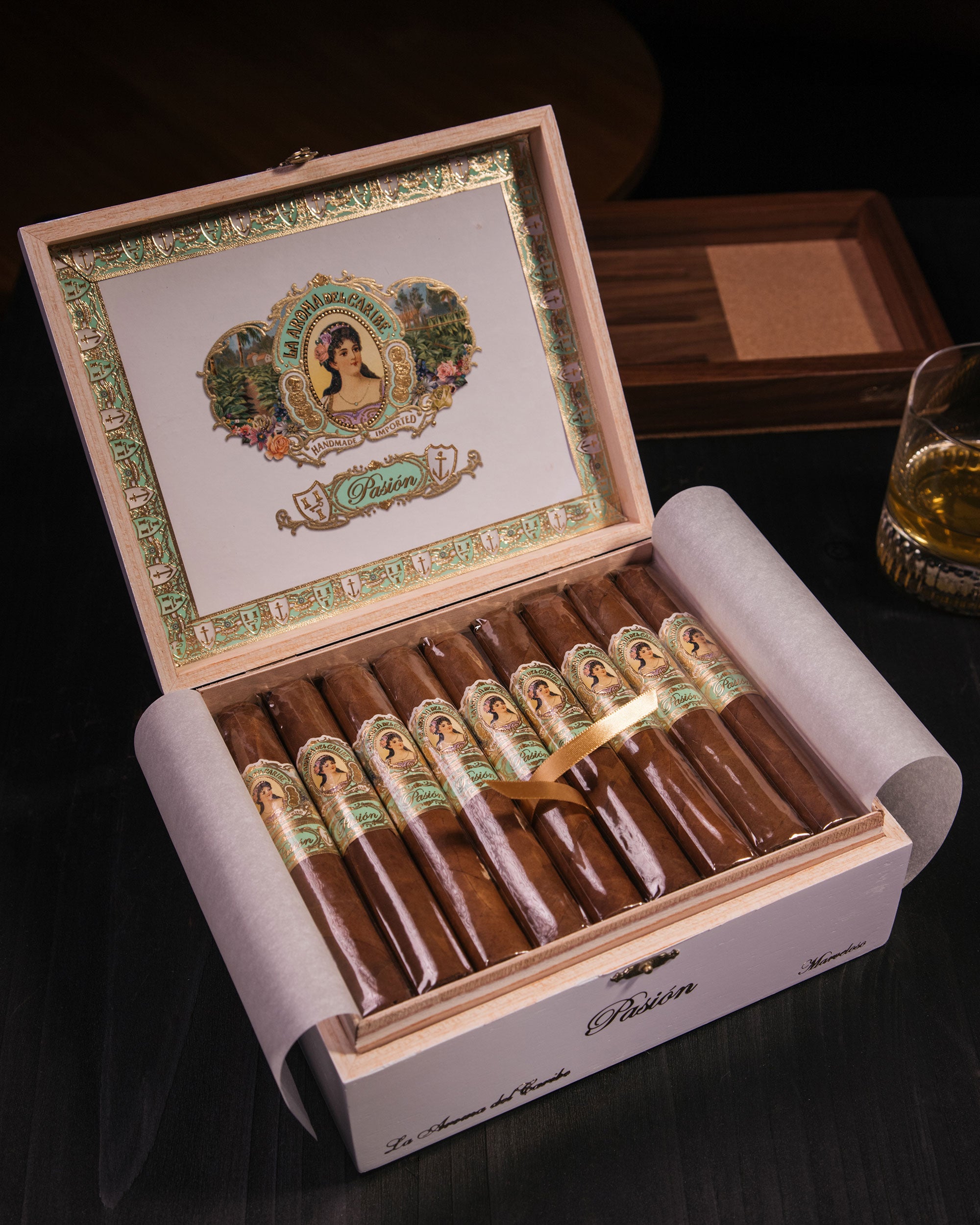 Open wooden humidor with cigars and decorative lid on a dark surface