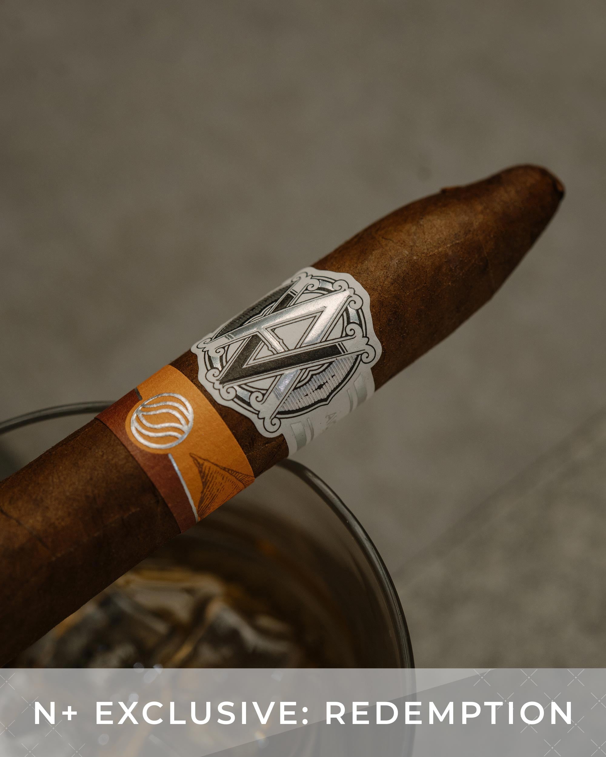Cigar with a label on a textured surface, featuring the text 'N+ Exclusive: Redemption'.