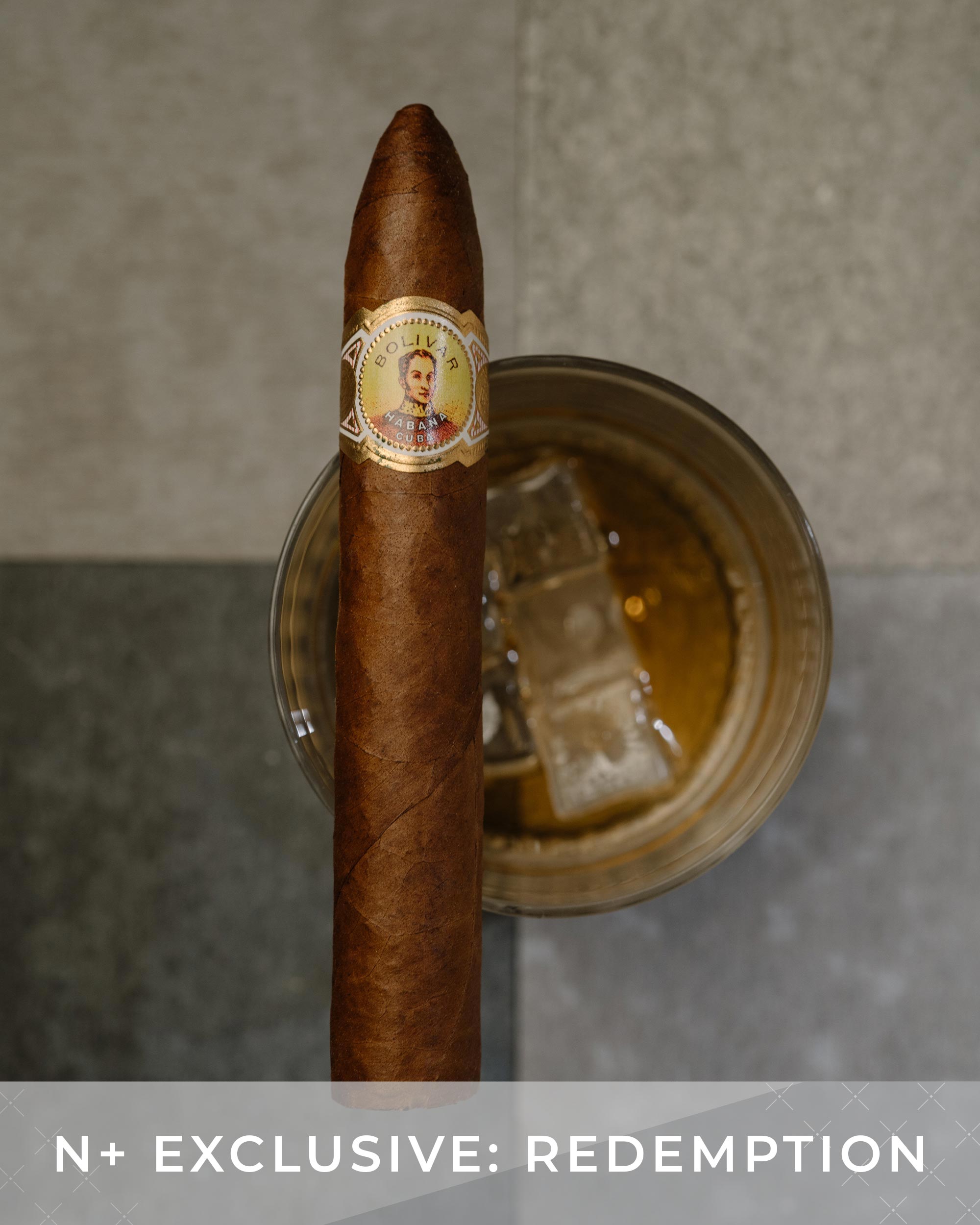 Cigar with a label on a glass of whiskey against a neutral background