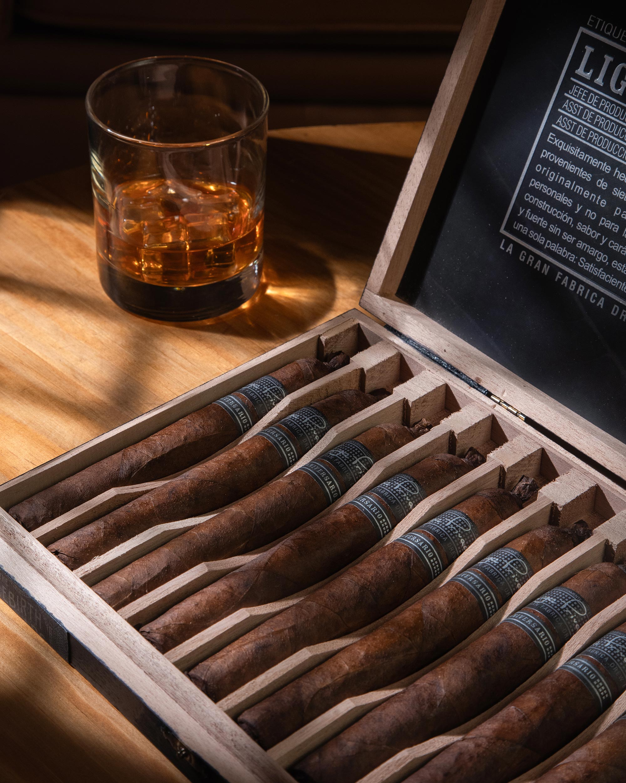 Box of cigars with a glass of whiskey on a wooden table