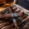 Cigars in a wooden box with a glass of whiskey on a wooden table.