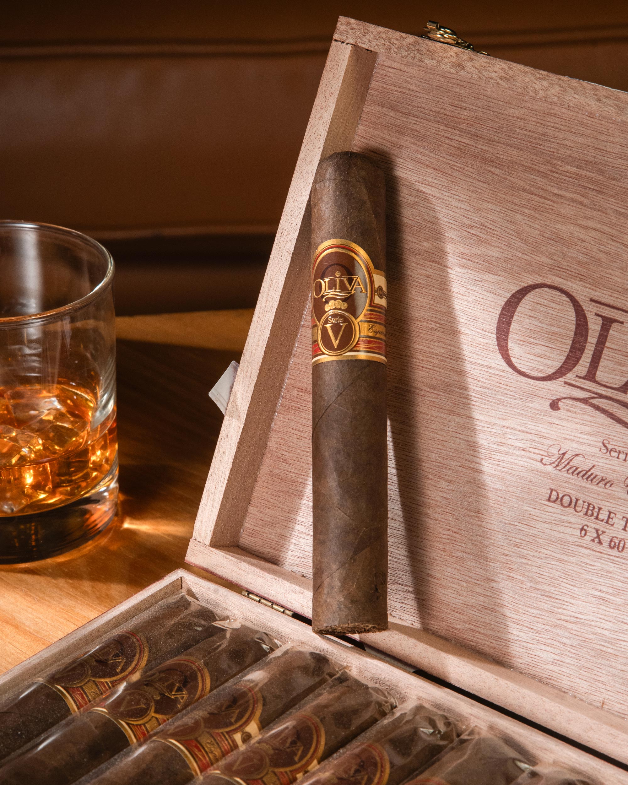 Cigar in a wooden box with a glass of whiskey on a wooden table