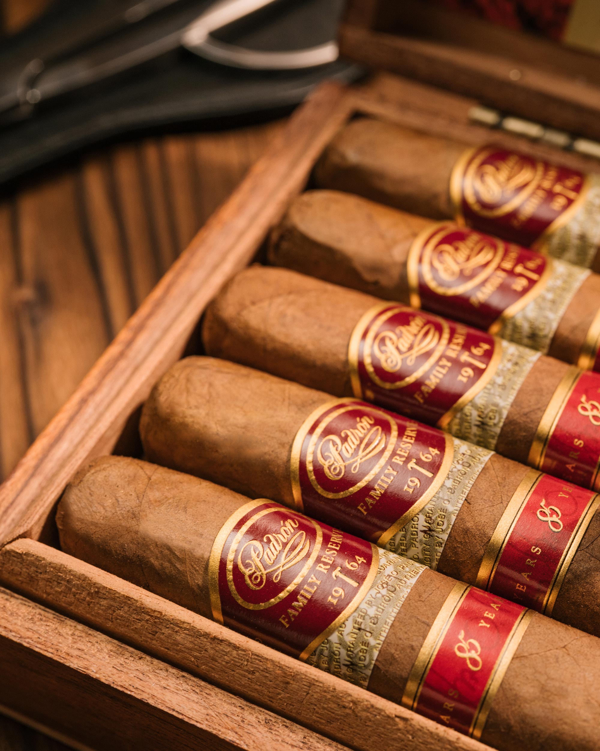 Row of cigars with red bands in a wooden humidor