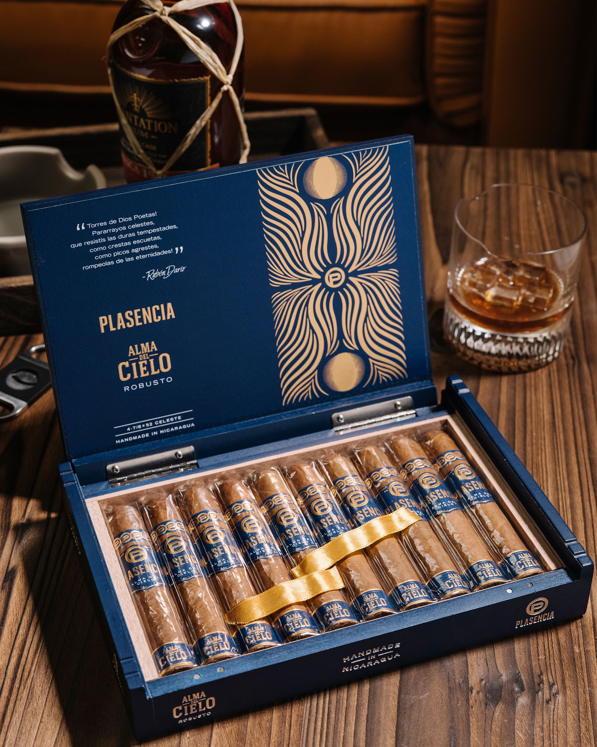 Open box of Plasencia cigars with a bottle of Havana Club rum in the background.