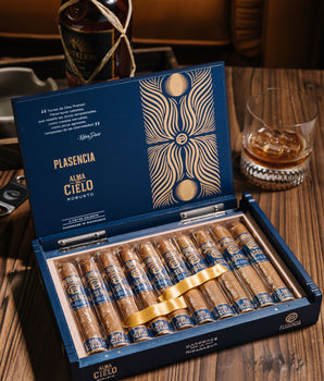 Open box of Plasencia cigars with a bottle of Havana Club rum in the background.