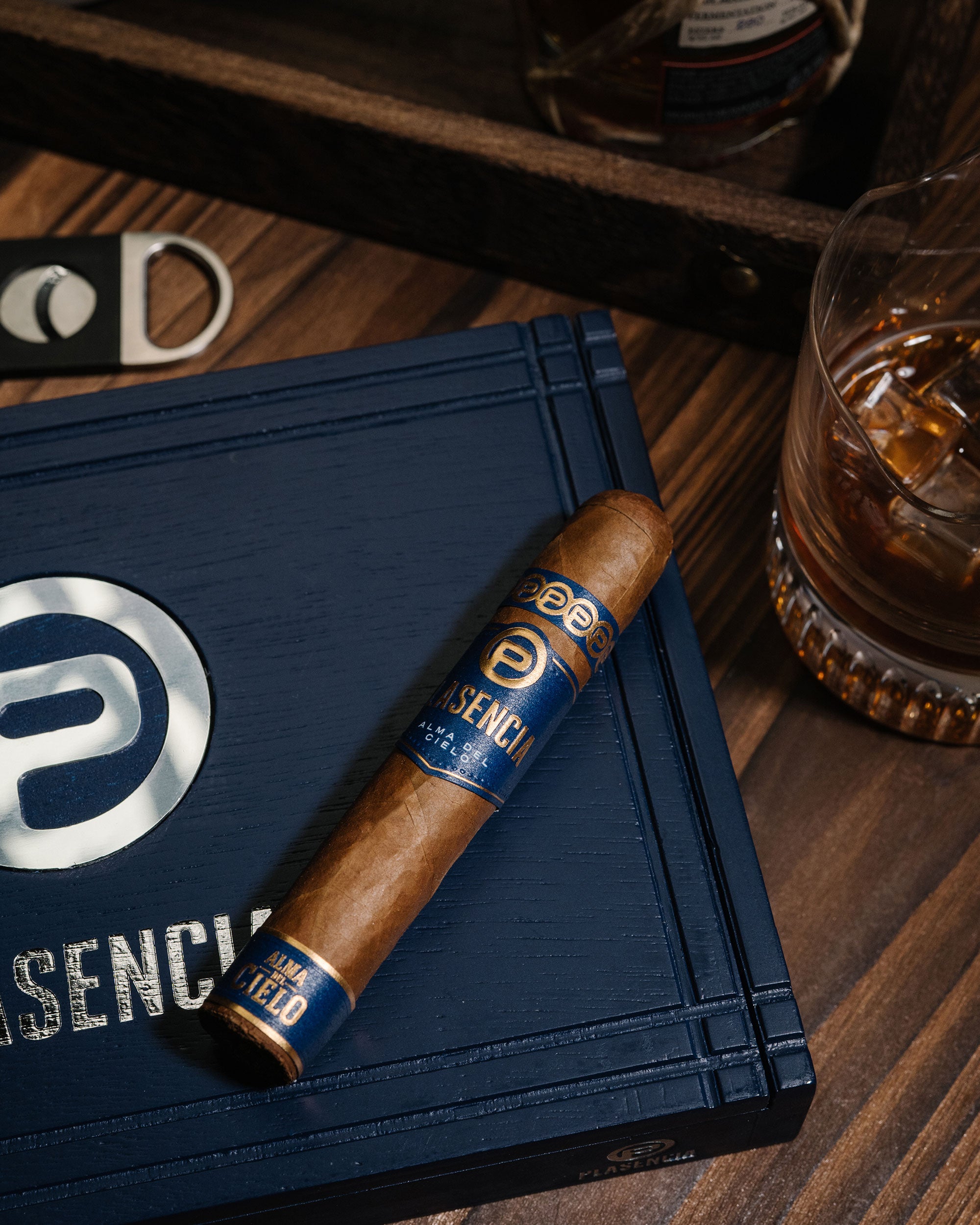 Cigar with blue band on a blue box labeled 'PRESENCE' on a wooden surface.