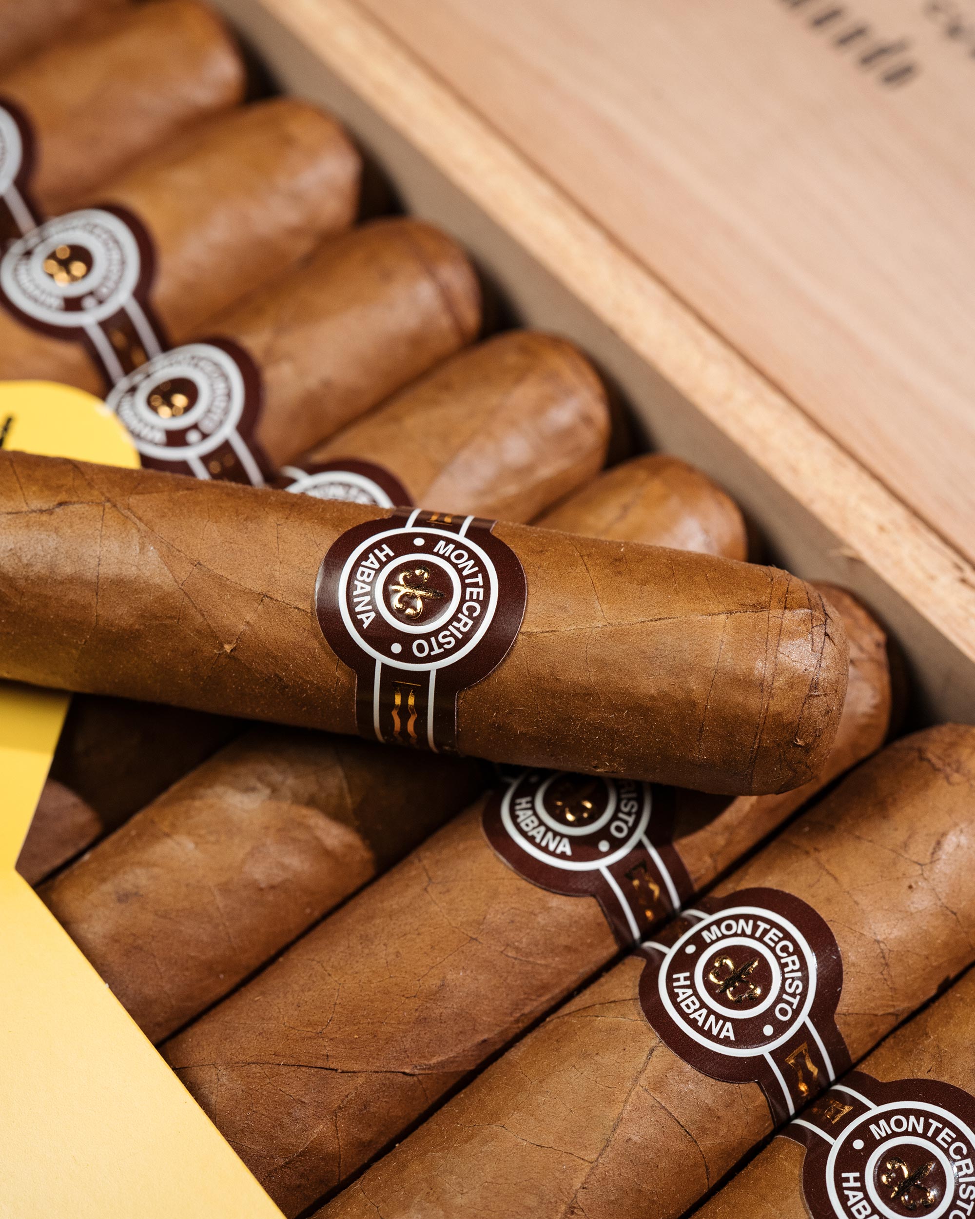 Close-up of Montecristo cigars with visible branding in a wooden box.
