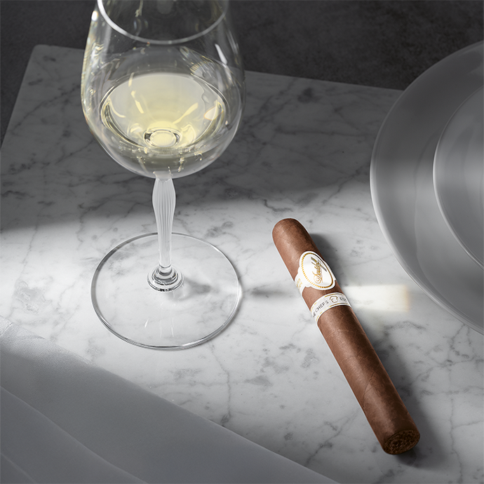 Wine glass with white wine and a cigar on a marble surface