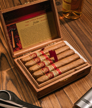Open wooden humidor with cigars on a wooden surface